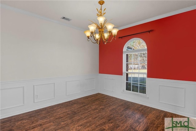 unfurnished room with visible vents, a wainscoted wall, ornamental molding, an inviting chandelier, and wood finished floors