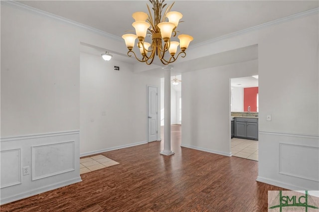 unfurnished dining area featuring crown molding, a decorative wall, wood finished floors, and a chandelier