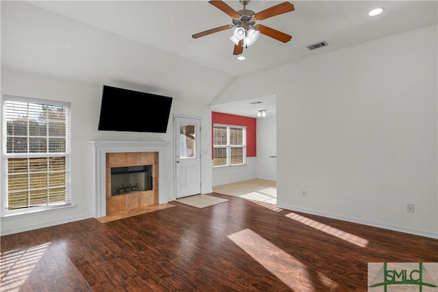 unfurnished living room featuring wood finished floors, visible vents, a wealth of natural light, and a tile fireplace