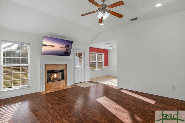 unfurnished living room featuring visible vents, wood finished floors, a fireplace, ceiling fan, and vaulted ceiling