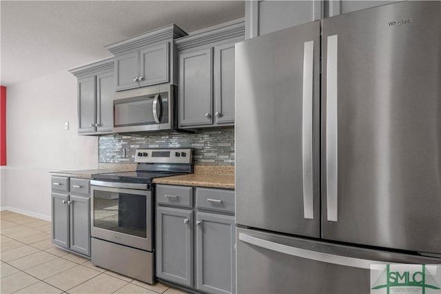 kitchen featuring tasteful backsplash, baseboards, light tile patterned floors, gray cabinets, and appliances with stainless steel finishes