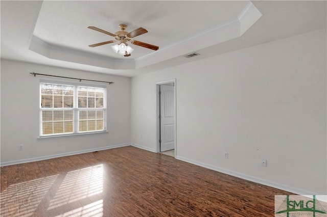 empty room featuring visible vents, a raised ceiling, baseboards, and ceiling fan