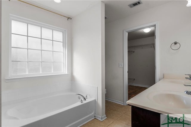 bathroom with tile patterned floors, visible vents, a bath, and a sink