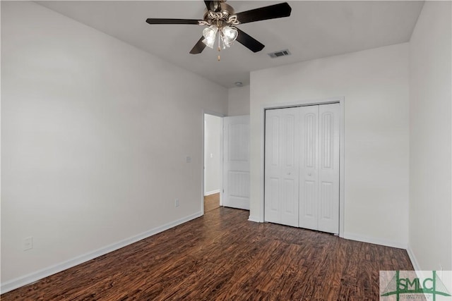 unfurnished bedroom with a closet, visible vents, dark wood-type flooring, and baseboards