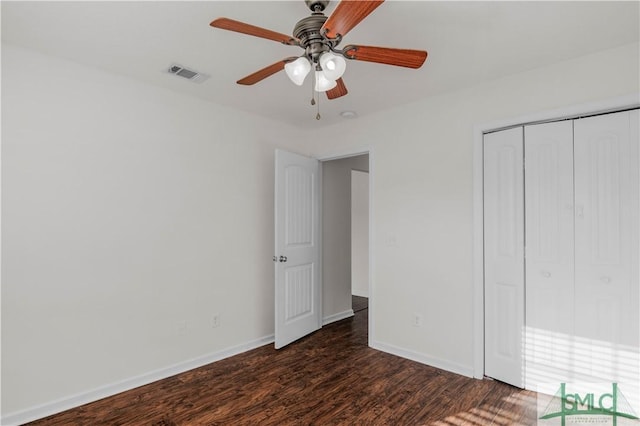 unfurnished bedroom with a closet, visible vents, baseboards, and dark wood-style flooring