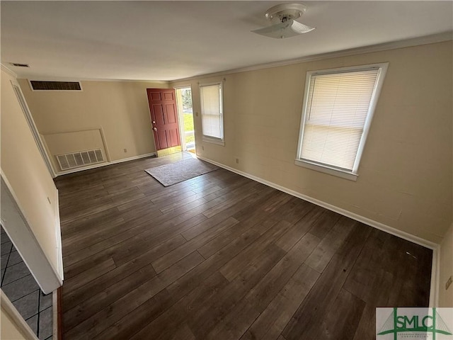 unfurnished room with visible vents, baseboards, dark wood-style floors, and crown molding