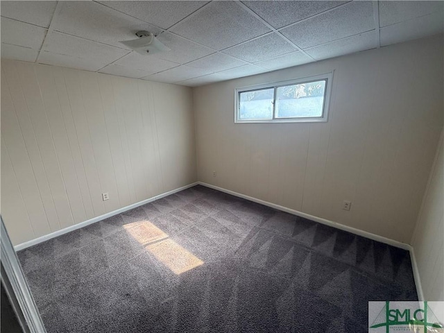 spare room featuring a paneled ceiling, carpet floors, and baseboards