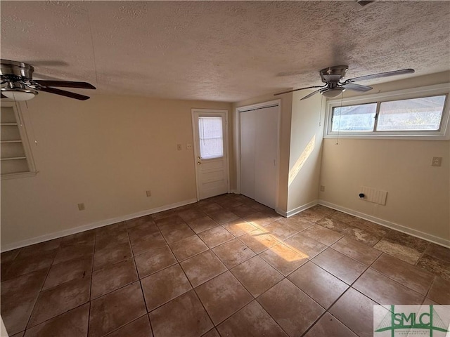 interior space featuring baseboards, plenty of natural light, a textured ceiling, and a ceiling fan