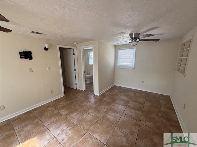 tiled spare room with visible vents, baseboards, and ceiling fan