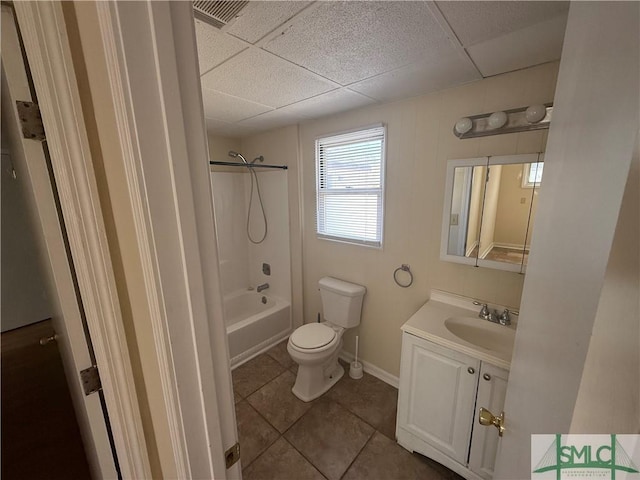 bathroom featuring tile patterned flooring, a drop ceiling, toilet, and vanity