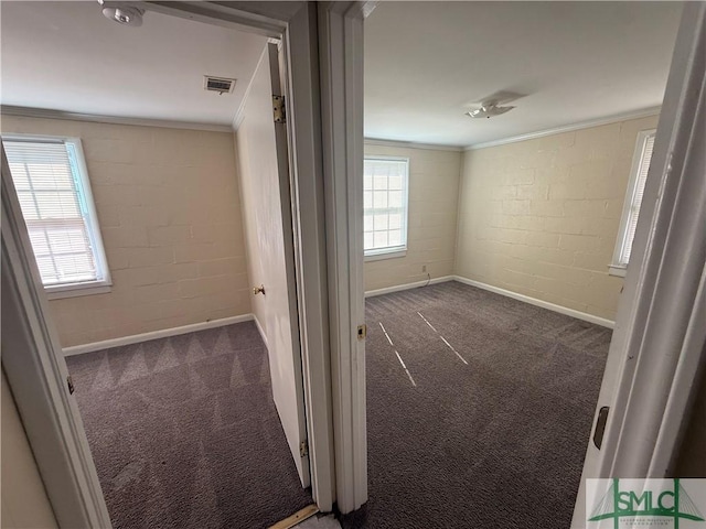 unfurnished bedroom featuring crown molding, concrete block wall, carpet flooring, and visible vents