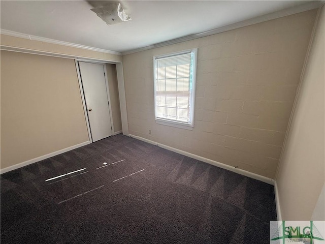 unfurnished bedroom featuring a closet, crown molding, baseboards, and dark colored carpet