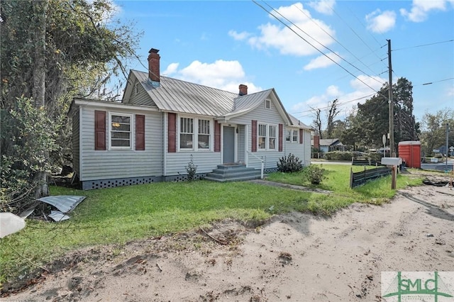 view of front facade featuring a front lawn, metal roof, and a chimney