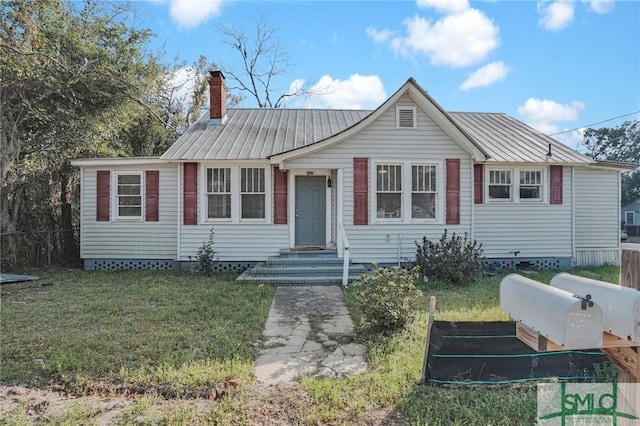 view of front of home featuring a front lawn, fence, a chimney, and metal roof