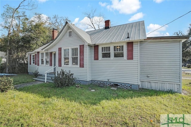 view of front of property with a front yard, metal roof, and a chimney