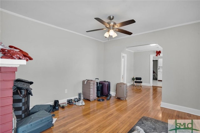 interior space featuring ornamental molding, a ceiling fan, wood finished floors, baseboards, and attic access