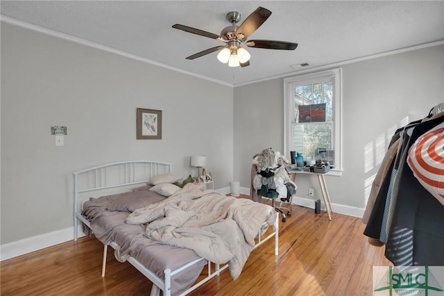 bedroom with light wood-type flooring, baseboards, visible vents, and ornamental molding