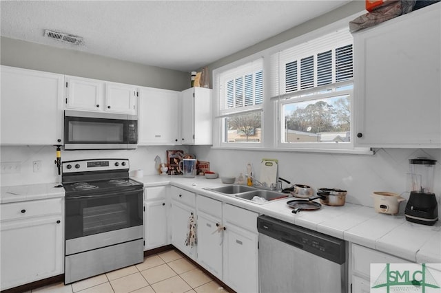 kitchen with visible vents, a sink, backsplash, appliances with stainless steel finishes, and white cabinets