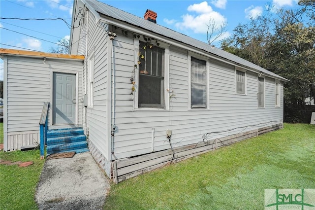 view of side of home with entry steps, a yard, and a chimney