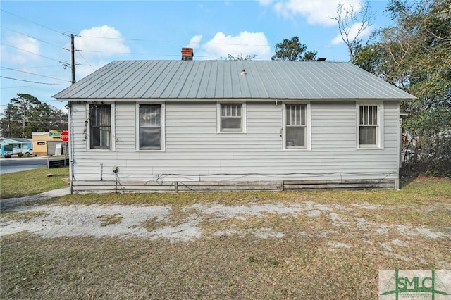 view of property exterior with a chimney and metal roof