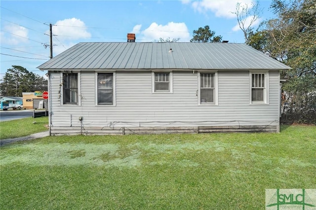 exterior space featuring a yard, a chimney, and metal roof