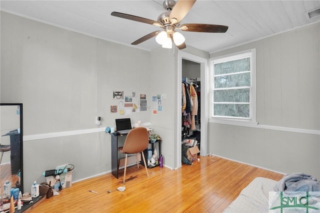 office area featuring hardwood / wood-style floors, crown molding, a ceiling fan, and visible vents