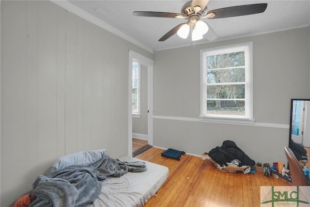 bedroom with wood finished floors, a ceiling fan, and ornamental molding