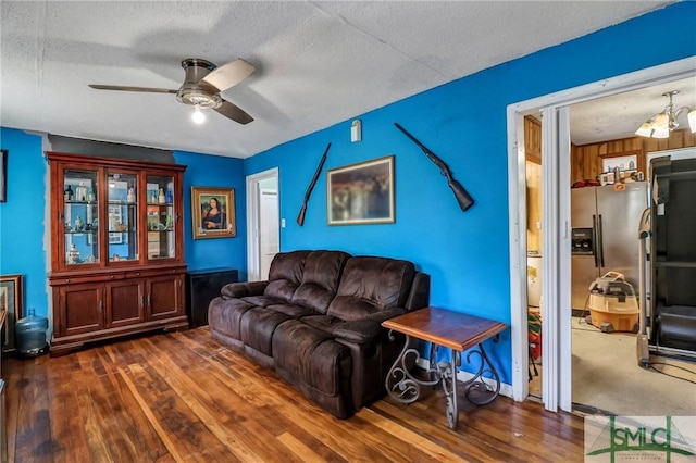 living room featuring baseboards, a textured ceiling, wood finished floors, and a ceiling fan