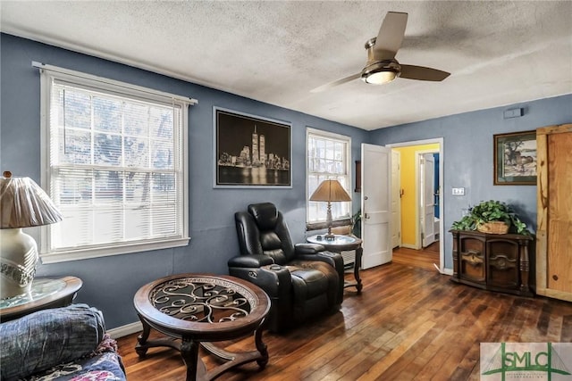 living area with baseboards, a textured ceiling, hardwood / wood-style floors, and a ceiling fan