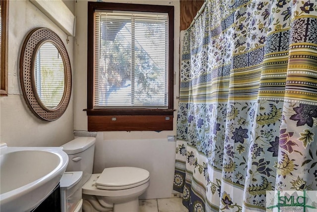 bathroom featuring tile patterned flooring, curtained shower, toilet, and a sink