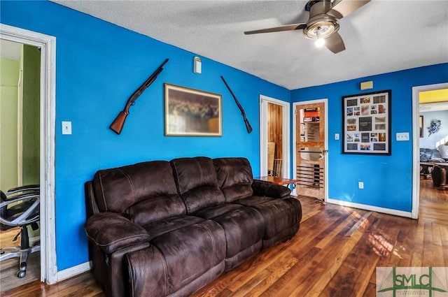 living area featuring baseboards, hardwood / wood-style floors, and a ceiling fan