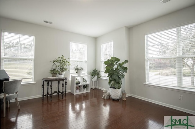living area with baseboards, visible vents, and hardwood / wood-style floors