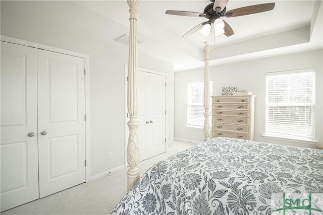 bedroom featuring visible vents, a ceiling fan, a tray ceiling, carpet, and baseboards