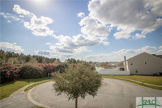view of home's community with fence and curved driveway
