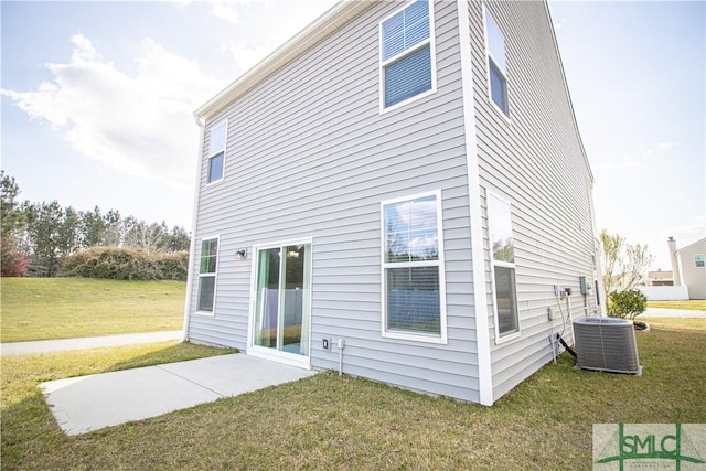 back of house featuring central air condition unit and a yard