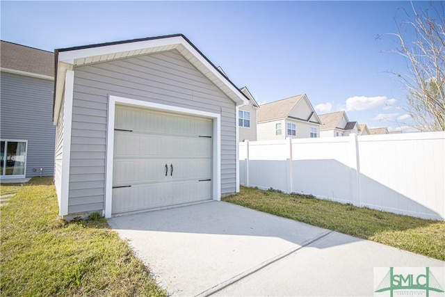 detached garage featuring fence and concrete driveway