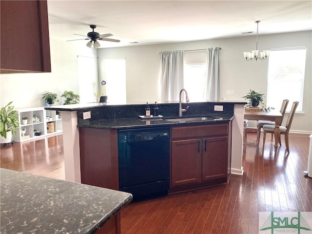 kitchen featuring dark wood-style flooring, a kitchen island with sink, black dishwasher, a sink, and ceiling fan with notable chandelier