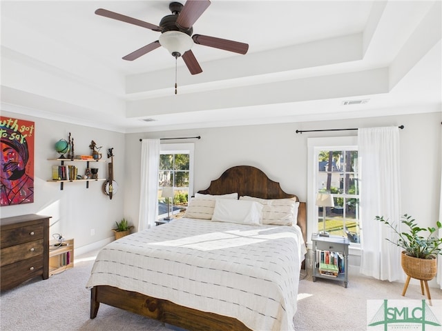 bedroom featuring ceiling fan, a raised ceiling, visible vents, and light carpet