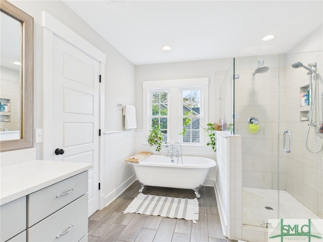 full bath featuring vanity, a wainscoted wall, wood finish floors, a freestanding tub, and a shower stall