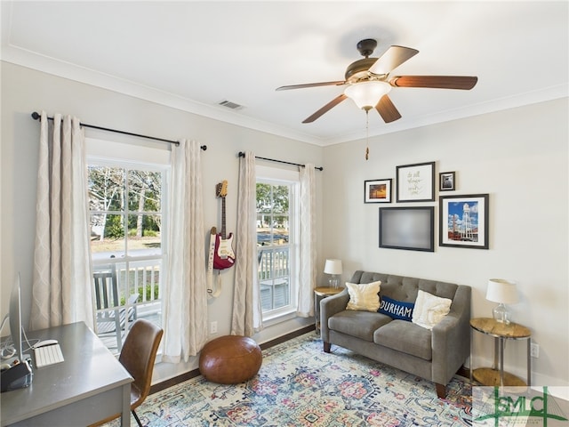 living area featuring visible vents, crown molding, baseboards, wood finished floors, and a ceiling fan