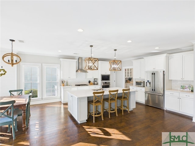 kitchen featuring light countertops, a notable chandelier, stainless steel appliances, wall chimney exhaust hood, and dark wood-style flooring