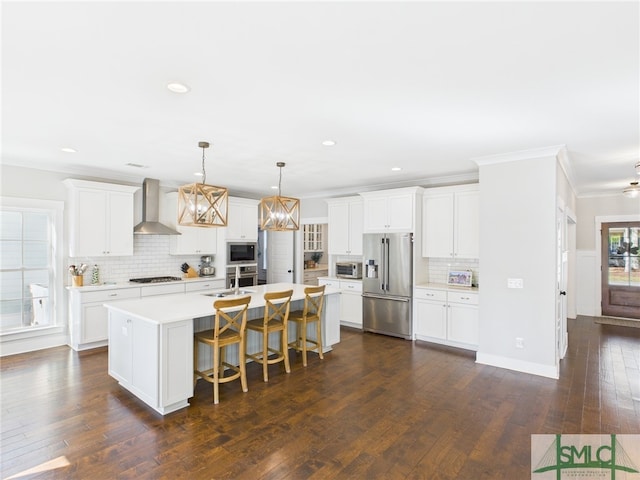 kitchen featuring dark wood-type flooring, a sink, stainless steel appliances, wall chimney exhaust hood, and light countertops