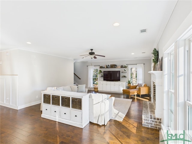 living room featuring dark wood finished floors, visible vents, a fireplace, and ornamental molding