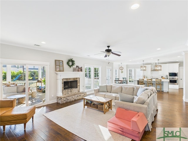 living area featuring dark wood-style floors, plenty of natural light, visible vents, and ceiling fan