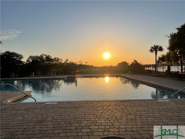 pool at dusk with a community pool and a patio area