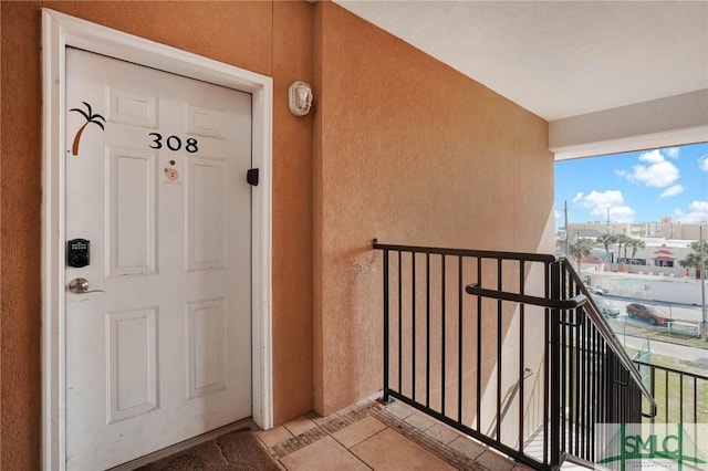 view of exterior entry featuring a balcony and stucco siding