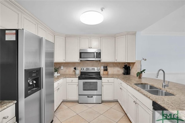 kitchen featuring tasteful backsplash, light tile patterned floors, light stone counters, stainless steel appliances, and a sink