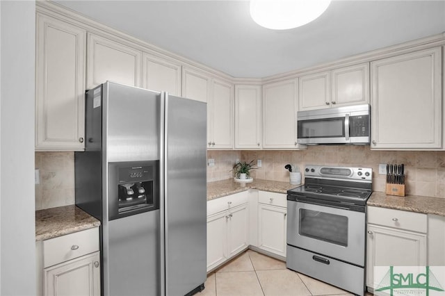 kitchen featuring light tile patterned floors, stainless steel appliances, light stone countertops, and decorative backsplash