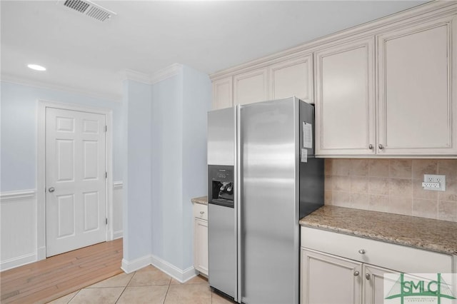 kitchen with visible vents, light tile patterned flooring, ornamental molding, stainless steel fridge, and backsplash