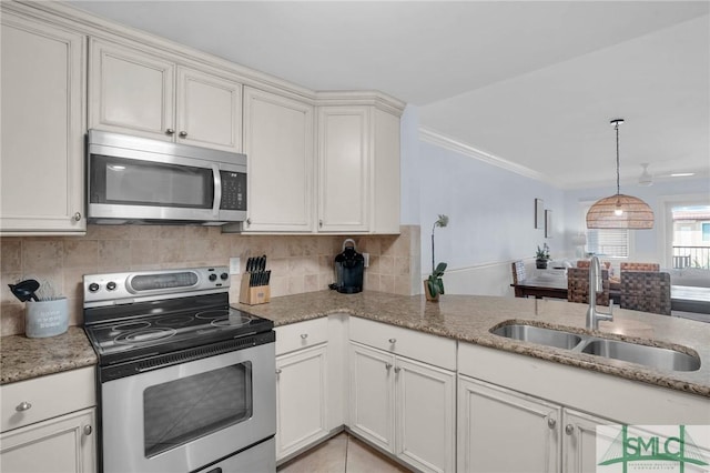 kitchen featuring light stone counters, decorative backsplash, appliances with stainless steel finishes, and a sink